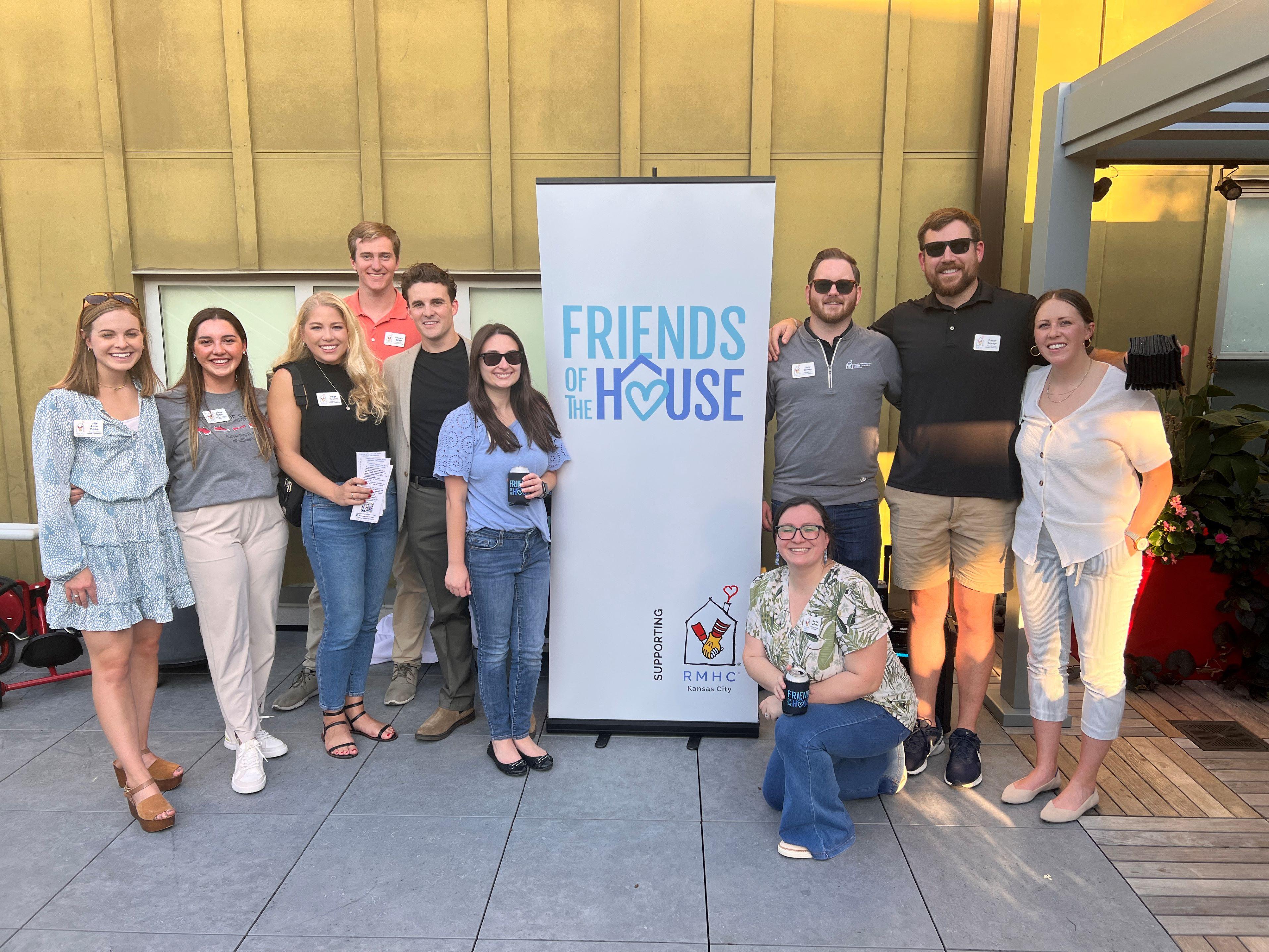 Friends of the House Leadership Team poses with their logo banner at the Membership Happy Hour event on the rooftop at RMHC-KC